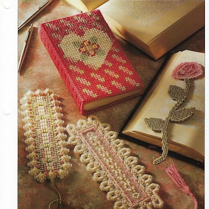 May include: A red book cover and several bookmarks. The book cover has a heart design. Two bookmarks have a decorative border and tassels. The text "BOOK COVER & BOOKMARKS" is at the top.