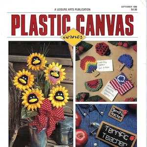 May include: A magazine cover for Plastic Canvas Corner, featuring 21 craft projects. The cover image shows a bouquet of sunflowers in a metal bucket, a watermelon slice, a ladybug, a rainbow, an umbrella, and a set of teacher name tags. The magazine cover text reads "21 Projects in this Issue! Sunny Face Flowers, Lullaby Bears, Seashells, Terrific Teacher Set."