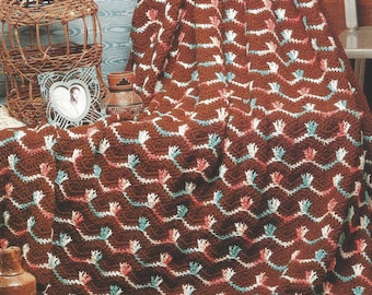 May include: A brown crochet afghan with a ripple pattern and white, pink, and teal accents. The afghan is called "Coral Isle" and is part of the "Collector's Series".