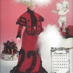 May include: A crochet doll in a red dress with black lace trim, a matching jacket, and a feathered hat. The doll has a calendar for December 1996 in the background. A white feather boa is draped over the doll's arm.