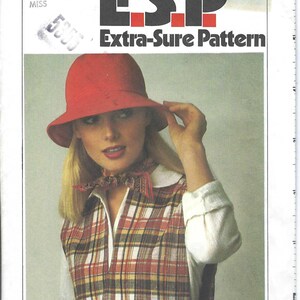 May include: A Simplicity sewing pattern for a plaid vest with a red hat. The pattern number is 8165 and the size is N (10, 12, 14) for misses.