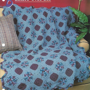 May include: A blue and purple crocheted throw blanket with a scalloped edge. The blanket is draped over a couch with a plaid pillow. The text "Berry Patch" is visible in the upper left corner of the image.