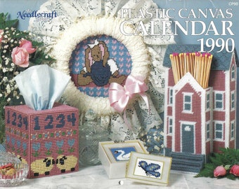 May include: Plastic canvas craft patterns for a calendar, tissue box cover, and match holder. The calendar is a house with a red roof and blue trim. The tissue box cover has a pink base with a sheep design. The match holder is a house with a red roof and blue trim. The patterns are from 1990.