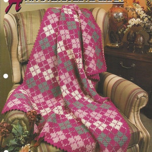 May include: A pink, white, and gray crocheted afghan with a diamond pattern is draped over a striped armchair. The afghan has a scalloped edge.