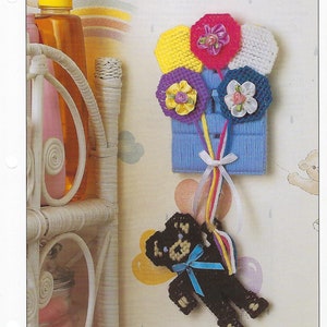 May include: A light blue plastic canvas switch cover with a teddy bear and a bouquet of colorful flowers. The flowers are made of plastic canvas and have a ribbon tied around the stem. The teddy bear is black and has a blue ribbon around its neck. The switch cover is decorated with the words "Teddy Bear Switch Cover" and "Home Decor".