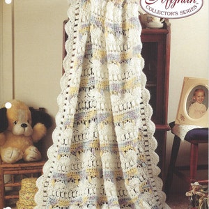 May include: A white crochet baby blanket with a scalloped edge and stripes of yellow, blue, and purple. The blanket is called "Rainbows & Clouds" and was designed by Maria Nagy.