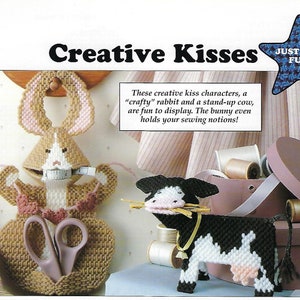 May include: A craft project featuring a brown rabbit and a black and white cow. The rabbit is holding a measuring tape and scissors. The cow is holding a bunch of straw. The text "Creative Kisses" and "Just for Fun" is visible in the image.