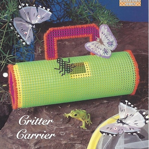 May include: A green and yellow plastic canvas critter carrier with a pink and orange handle. The carrier has a small opening on the side. The image also includes butterflies and frogs. The text "Critter Carrier" is written below the carrier.