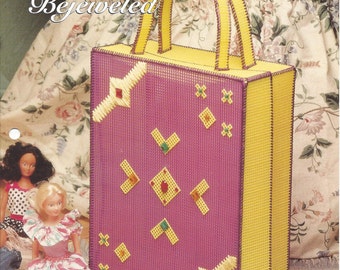 May include: A plastic canvas tote bag with a purple body and yellow accents. The bag features stitched geometric designs in yellow, red, and green. The text "Bright & Bejeweled" is visible on the cover. The bag has yellow handles.