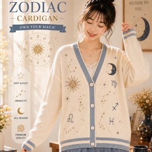 May include: A cream-colored V-neck cardigan featuring blue trim on the cuffs, hem, and placket. The knit garment is decorated with gold and blue celestial motifs, including a sun, a crescent moon, various star patterns, and zodiac symbols.