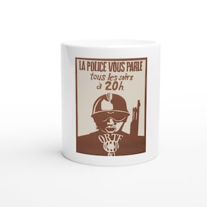 May include: A white ceramic mug featuring a brown graphic print of a person wearing a helmet and goggles, holding a rifle. The text reads: LA POLICE VOUS PARLE tous les soirs à 20h. Below the figure, the letters ORTF are printed above a microphone icon.