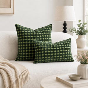 May include: Two dark green and light green textured scatter cushions with a repeating geometric diamond pattern. One cushion is square and the other is rectangular, both featuring a soft, raised fabric construction with a consistent colour scheme.