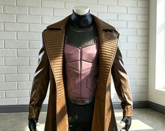 May include: A brown leather trench coat worn over a black and mauve padded chest piece with a high collar. The outfit includes a belt featuring a red X emblem and black fingerless gloves, displayed on a mannequin against a white brick wall.