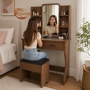 May include: A wooden vanity table with a central mirror, side shelving units, and a single drawer. The vanity includes a matching wooden stool with a black padded seat. The structure features a warm brown wood grain finish and open storage.
