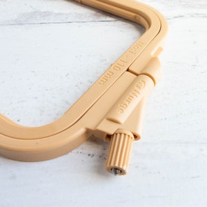 May include: A beige embroidery hoop with the text "No. 1 - 110 mm" and the brand name "Nurge". The hoop is made of plastic and has an adjustable screw for tightening fabric. The hoop is designed for embroidery and needlework projects.