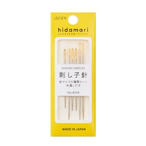 May include: A package of Sashiko needles by Lecien. The yellow and white package features the brand name "hidamari" and Japanese text. The package contains several gold-toned needles of varying lengths, designed for Sashiko stitching. The text "MADE IN JAPAN" is printed at the bottom.
