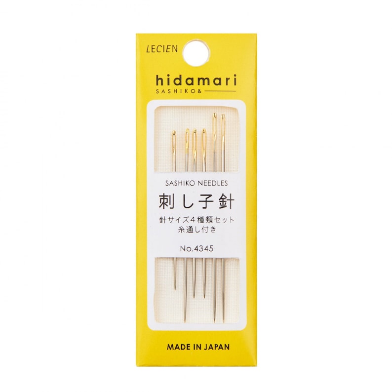 May include: A package of Sashiko needles by Lecien. The yellow and white package features the brand name "hidamari" and Japanese text. The package contains several gold-toned needles of varying lengths, designed for Sashiko stitching. The text "MADE IN JAPAN" is printed at the bottom.