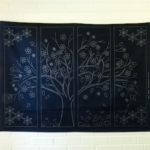 May include: A dark blue fabric panel featuring a tree design with white stitched details. The tree is adorned with flowers and leaves, and the panel is divided into four sections. The design includes star-shaped floral accents.