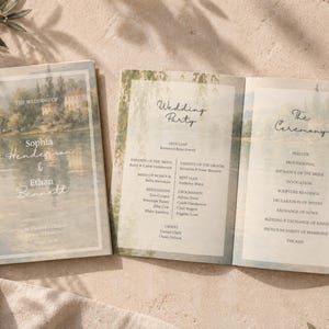 May include: A folded wedding programme featuring a watercolour landscape of a lake and building. The front cover displays the names Sophia Henderson and Ethan Bennett. The interior panels list the wedding party and the ceremony order of events.
