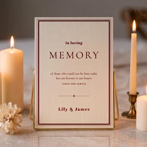 May include: A rectangular memorial sign with a cream-colored background and a dark red border. The text reads: in loving MEMORY of those who could not be here today but are forever in our hearts TODAY AND ALWAYS Lily & James. It sits on a gold stand.