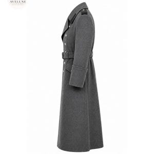 May include: A long, charcoal gray wool-blend overcoat featuring a double-breasted front with silver-toned buttons, a matching waist belt with a buckle, structured lapels, shoulder epaulets, and wide cuffs, presented in a side profile view.