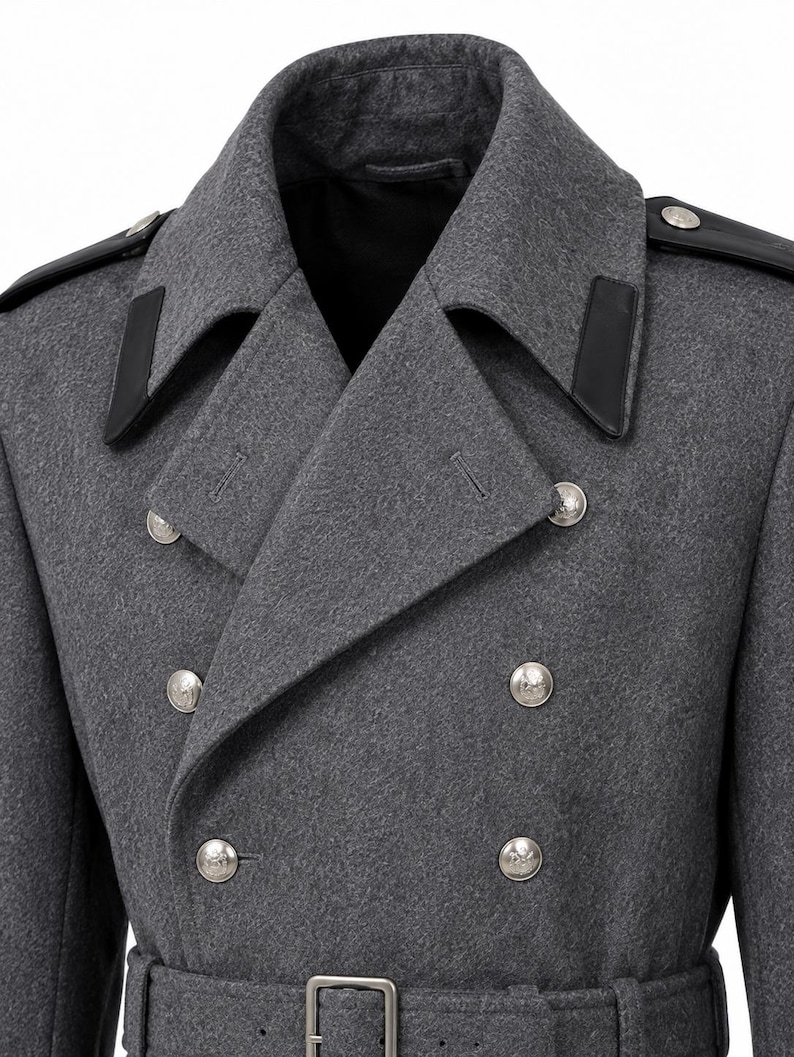 May include: A double-breasted charcoal gray wool coat featuring a wide notched lapel, black leather shoulder epaulets, and black leather collar accents. The coat is secured with two columns of silver-toned metal buttons and a matching waist belt.