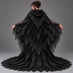 Könnte beinhalten: Ein schwarzer, bodenlanger Umhang mit Kapuze, der ein komplexes Häkeldesign mit geschichteten, blattartigen Texturen aufweist, die den Rücken hinunterfallen. Das Kleidungsstück hat weite, offen gewebte Ärmel und einen vollen Saum.