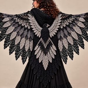Peut inclure: Un châle au crochet noir et gris présentant un motif d'oiseau complexe avec des ailes déployées dans le dos. Le vêtement comprend une capuche et est réalisé avec des motifs au crochet en forme de plumes superposées dans des tons alternés.