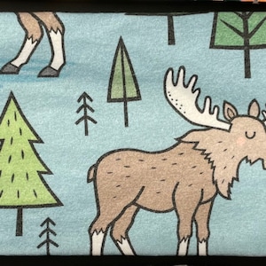 Puede incluir: Una diadema de tela azul con un patr&oacute;n repetido de alces, &aacute;rboles y ciervos. Los alces son marrones con grandes cuernos, los &aacute;rboles son verdes y los ciervos son marrones con manchas blancas.