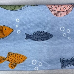 以下が含まれることがあります： オレンジとブルーの魚、ピンクとグリーンの円、白い泡が繰り返されるパターンが施された青いヘッドバンドです。
