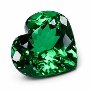 May include: A heart-shaped gemstone with a vibrant emerald green color and a faceted surface. The stone features multiple geometric cuts that reflect light, creating a brilliant, sparkling appearance with deep and light green tones throughout.