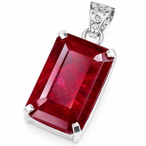 Puede incluir: Un colgante rectangular de piedra preciosa de color rojo intenso montado en un marco de metal plateado con cuatro garras. El colgante presenta un pasador triangular decorativo en la parte superior, adornado con pequeñas piedras claras.