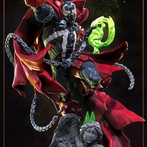 May include: A Spawn action figure featuring a black suit with white chest markings, a flowing red cape, and silver chains. The character holds a swirling green energy effect and stands atop a gray stone-textured base depicting a winged angel statue.