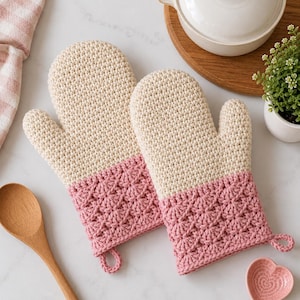 Peut inclure: Une paire de gants de cuisine bicolores avec une partie supérieure crème en maille crochetée serrée et une partie inférieure rose poudré avec un motif en éventail texturé. Chaque gant possède une petite boucle à la base pour le rangement.