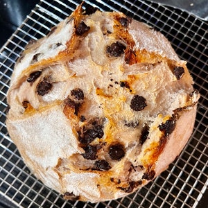May include: A close-up of a freshly baked loaf of bread with chocolate chips. The bread has a light brown crust and a soft, fluffy interior. The chocolate chips are evenly distributed throughout the bread.