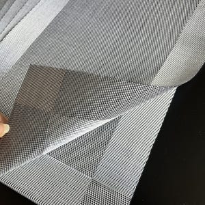Puede incluir: Un conjunto de manteles individuales rectangulares con una textura tejida en forma de rejilla en tonos grises. El material presenta un patrón entrecruzado con una estructura de tejido visible, con la pieza superior parcialmente doblada.