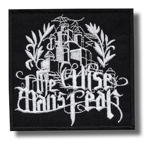 Può includere: Una toppa quadrata ricamata nera con dettagli in filo bianco. Il design include una struttura a castello stilizzata circondata da rami frondosi e il testo "The Wise Man's Fear" scritto con un carattere decorativo di ispirazione gotica.