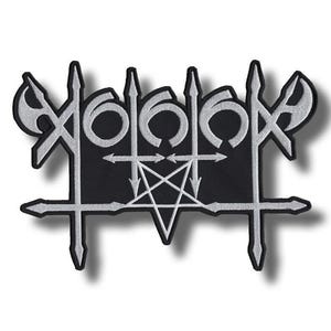 Könnte beinhalten: Ein schwarzer bestickter Aufnäher mit einem weißen stilisierten Logo aus scharfen, kantigen Buchstaben und geometrischen Symbolen. Das Design enthält ein zentrales Pentagramm, das mit kreuzartigen Formen und spitzen Klingen verbunden ist.