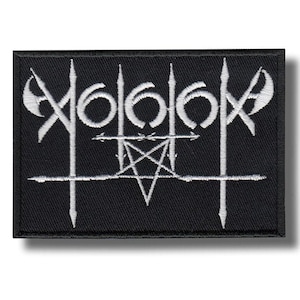 May include: A rectangular black embroidered patch featuring white thread detailing. The design consists of stylised, sharp-edged lettering combined with a central pentagram symbol and vertical spear-like elements across the entire surface.