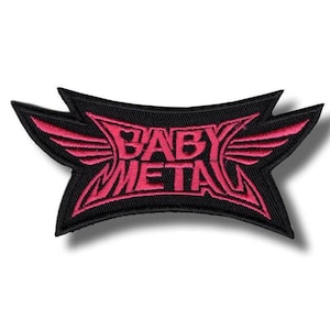 Könnte beinhalten: Ein bestickter Aufnäher mit schwarzem Hintergrund und einem stilisierten, scharfkantigen Design aus leuchtend rosa Garn. Der Text BABY METAL ist mittig platziert und von flügelartigen Formen umgeben, die sich zu den Seiten hin erstrecken.