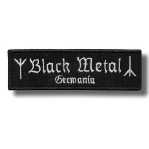 Könnte beinhalten: Ein rechteckiger schwarzer Stoffaufnäher mit weißer Stickerei, die den Schriftzug Black Metal Germania zeigt. Das Design umfasst ein stilisiertes Runensymbol auf der linken Seite und ein dreizackartiges Symbol auf der rechten Seite, umrandet von einer schwarzen Naht.