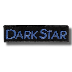 Op de afbeelding: Een rechthoekige geborduurde patch met een zwarte achtergrond en de tekst DARK STAR gestikt in lichtblauw garen. De letters zijn in een vetgedrukt schreefloos lettertype en de patch is afgewerkt met een dunne, zwart gestikte rand.
