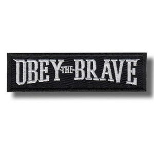 May include: A rectangular black embroidered patch featuring the white text OBEY THE BRAVE in a bold, serif font. The patch has a clean, stitched border and a flat, textured surface, designed for application onto fabric items like clothing or bags.