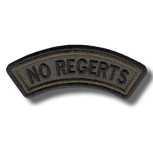 May include: A curved, embroidered patch featuring an olive green background with a black border. The text NO REGERTS is stitched in black, bold, capital letters across the center of the patch, which has a distinct arc shape.