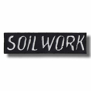 Può includere: Una toppa rettangolare ricamata nera con il testo bianco SOILWORK in un carattere stilizzato e leggermente usurato. La toppa presenta un bordo cucito pulito ed è progettata per essere applicata su tessuti come indumenti o borse.