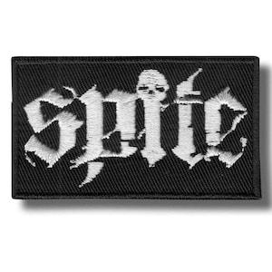 May include: A rectangular black embroidered patch featuring white thread stitching. The design displays the word "spite" in a stylised, jagged gothic font, with a small skull icon integrated into the letter "i" in the centre of the text.