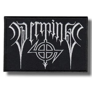 May include: A rectangular black embroidered patch featuring white thread stitching. The design displays stylised white lettering that reads "Vermine" above a circular symbol with a cross and two lightning bolt shapes extending from the centre.
