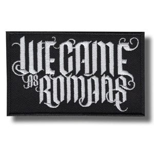 Op de afbeelding: Een rechthoekige zwarte geborduurde patch met de witte tekst WE CAME AS ROMANS in een gestileerd gotisch lettertype. Het borduurwerk heeft een dichte, getextureerde uitstraling met een zwarte rand die de witte letters op een zwarte achtergrond omlijst.