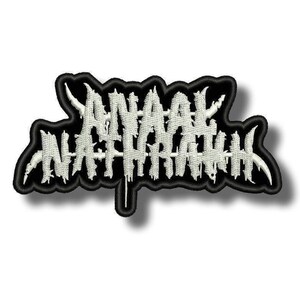 以下が含まれることがあります： 白くギザギザとした独特なフォントで「ANAAL NATHRAKH」という文字が刺繍されたワッペン。黒い背景に太い黒の縁取りが施されており、鋭く尖ったエッジを持つコントラストの強いデザインに仕上がっています。