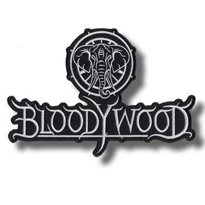 Puede incluir: Un parche bordado en blanco y negro que presenta un emblema circular con una cabeza de elefante estilizada en la parte superior. Debajo del emblema, el texto BLOODYWOOD está escrito en una fuente blanca decorativa sobre fondo negro.